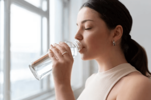 Una giovane ragazza che beve dell'acqua da una borraccia trasparente